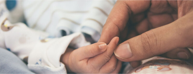 adult holding baby hand